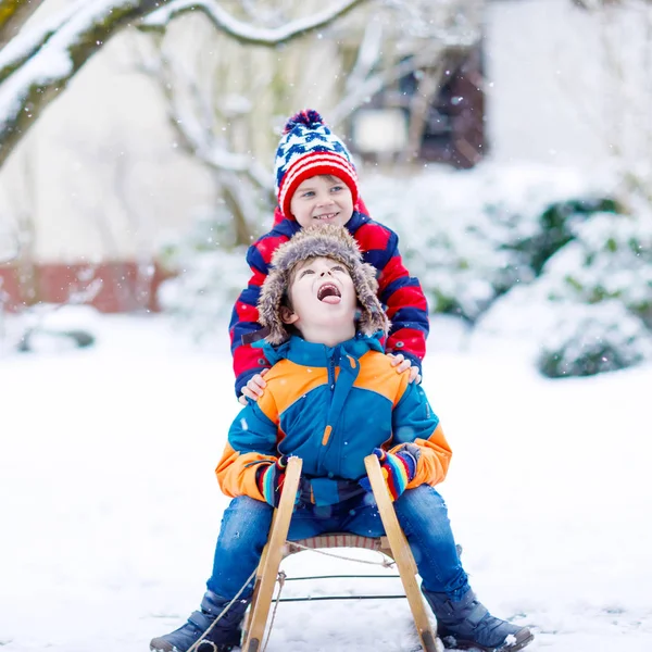 Два маленьких мальчика наслаждаются катанием на санях зимой — стоковое фото
