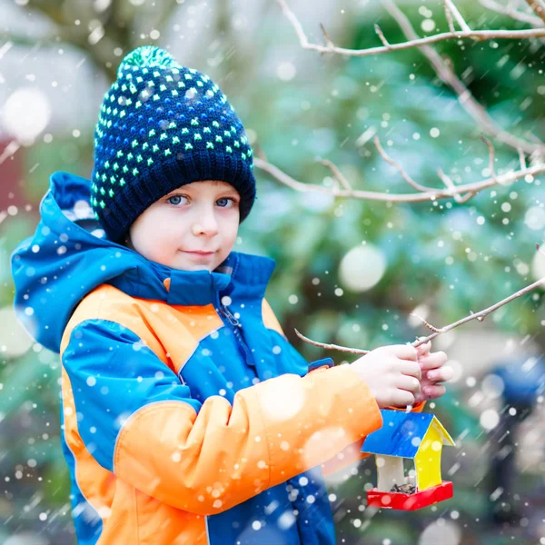 Küçük çocuk çocuk kuş evi kış aylarında beslenme için ağaç üzerinde asılı