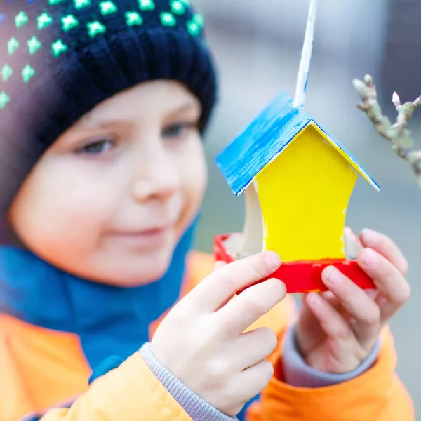 Маленький ребенок висит птичий домик на дереве для кормления зимой — стоковое фото