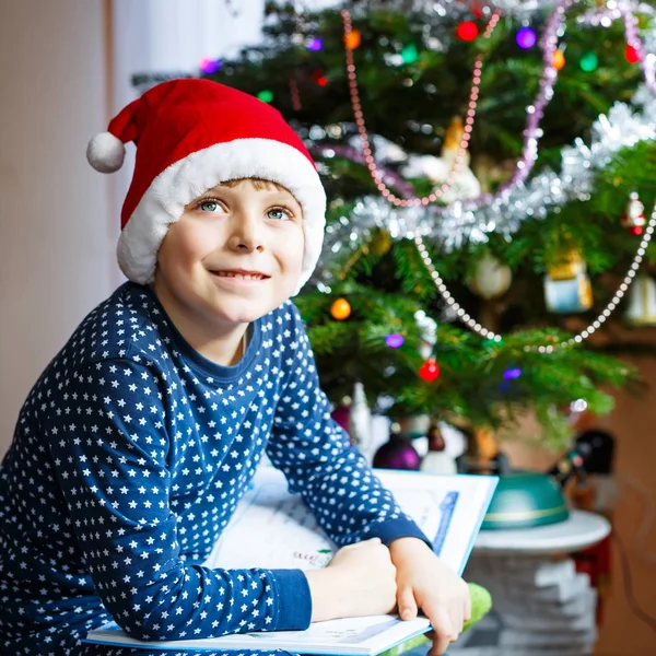 Kleiner Schuljunge liest ein Buch über Weihnachten — Stockfoto