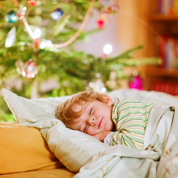 Kleiner süßer Junge schläft unter dem Weihnachtsbaum — Stockfoto