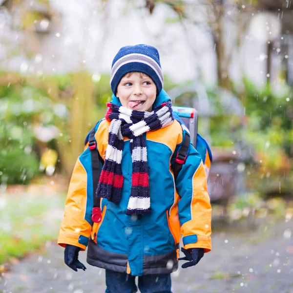 Menino feliz se divertindo com neve a caminho da escola — Fotografia de Stock