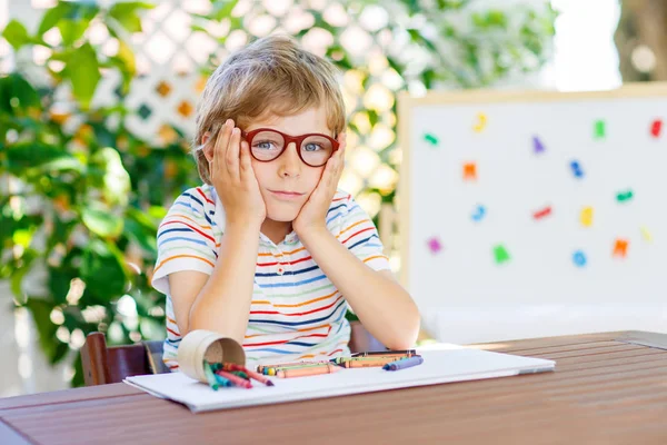 Menino menino da escola com óculos segurando lápis de cera — Fotografia de Stock