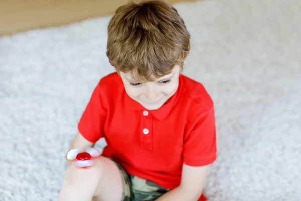 Niño de la escuela jugando con Tri Fidget Hand Spinner en interiores — Foto de Stock