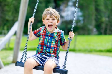 Açık sahada güneşli günde eğleniyor zinciri salıncak ile komik çocuk çocuk