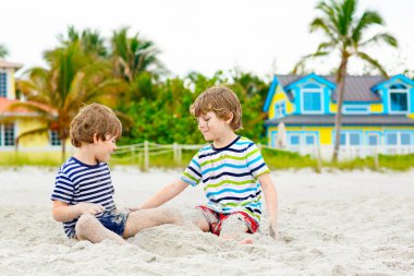 İki küçük çocuk tropik sahilde eğleniyor.