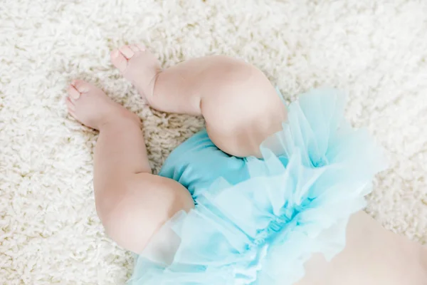 Närbild på ben och fötter med baby girl på vit bakgrund bär turkos tutu kjol. — Stockfoto