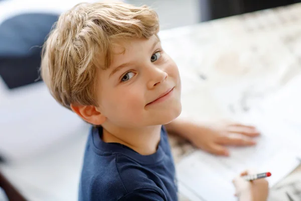 Feliz niño sonriente en casa haciendo deberes escribiendo cartas con plumas de colores —  Fotos de Stock