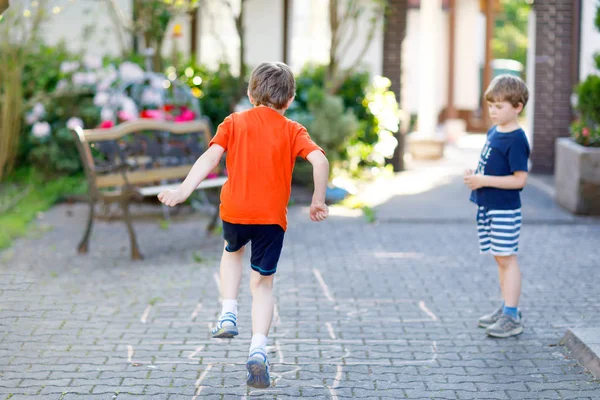 Twee kleine school en kleuters spelen hopscotch op de speelplaats — Stockfoto