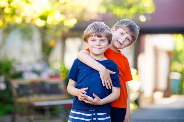 Two little active school kids boys, twins and siblings hugging on summer day — Stock Photo, Image