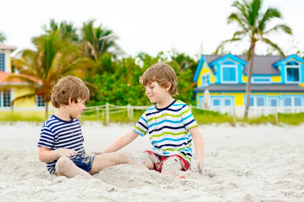 İki küçük çocuk tropik sahilde eğleniyor.