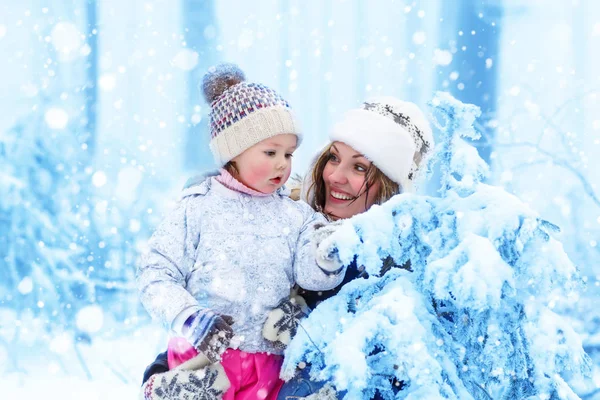 Счастливая семья с молодой мамой и маленькой дочкой на зимней прогулке на свежем воздухе . — стоковое фото