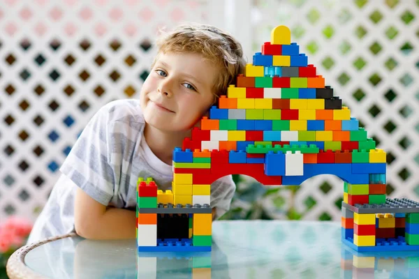 Klein blond kind en kind jongen spelen met veel kleurrijke plastic blokken. — Stockfoto