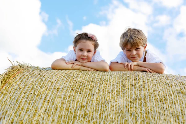 Nahaufnahme von zwei Kindern, die auf Heuballen im Weizenfeld liegen. — Stockfoto