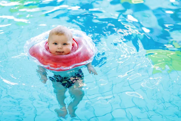 Cute little baby child learning to swim with swimming ring in an indoor pool — Stock Photo, Image