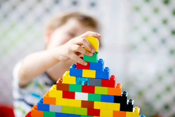 Kleines blondes Kind und kleiner Junge spielen mit vielen bunten Plastikklötzen. — Stockfoto