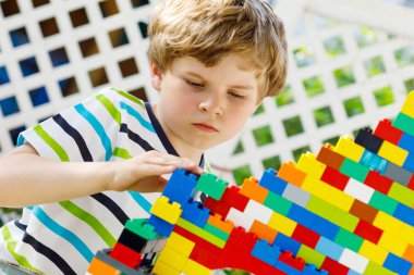 Küçük sarışın çocuk ve çocuk bir sürü renkli plastik blokla oynuyorlar..