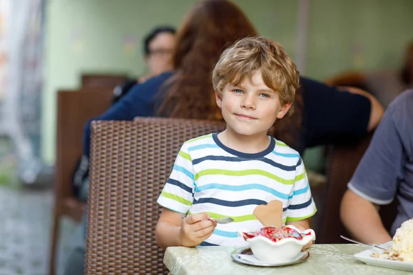 Mały chłopiec dziecko jeść lody w kawiarni na świeżym powietrzu lub w restauracji. — Zdjęcie stockowe