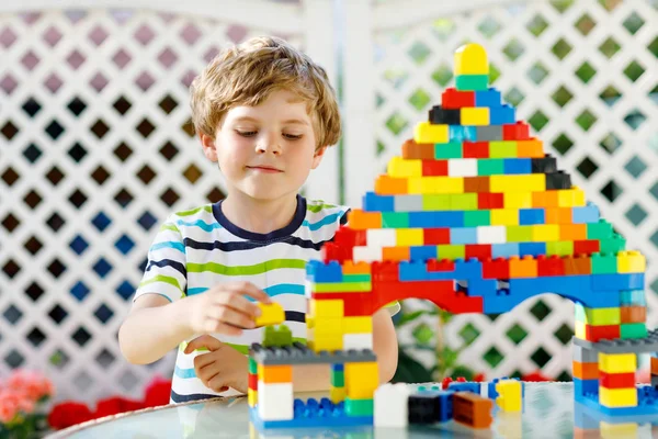 Klein blond kind en kind jongen spelen met veel kleurrijke plastic blokken. — Stockfoto