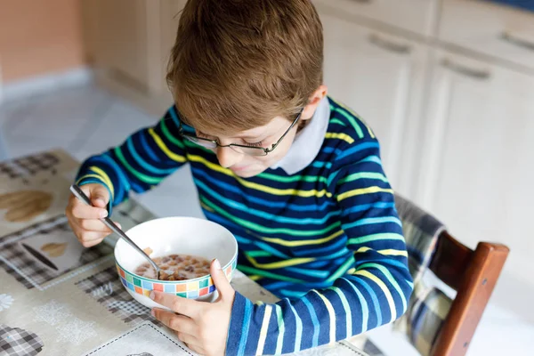 Menino loiro feliz comendo cereais no café da manhã ou almoço. Alimentação saudável para crianças . — Fotografia de Stock