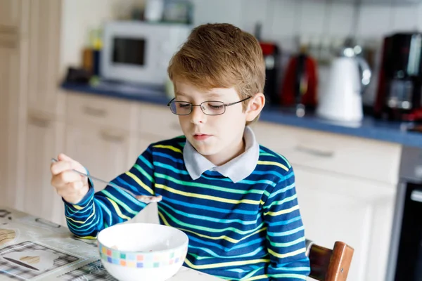 Joyeux petit garçon blond qui mange des céréales pour le petit déjeuner ou le déjeuner. Une alimentation saine pour les enfants . — Photo