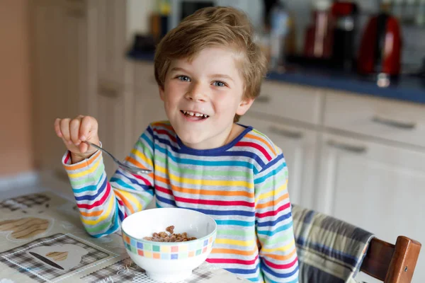 Happy little blond kid boy eating cereals for breakfast or lunch. Healthy eating for children. — Stock Photo, Image