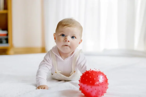 Söt baby leka med rött tuggummi boll, krypa, ta tag — Stockfoto