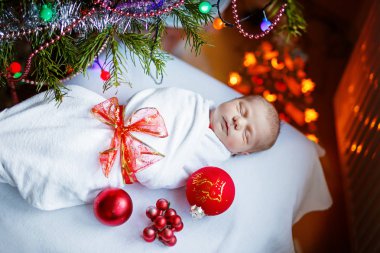 Noel ağacı yakınındaki battaniyeye sarılmış bir hafta eski yeni doğan bebek