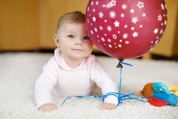 Bebê bonito brincando com balão de ar vermelho, rastejando, agarrando — Fotografia de Stock