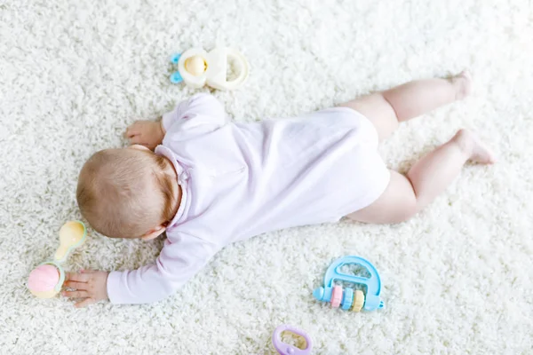Close-up of baby body and legs with lots of colorful rattle toys. — Stock Photo, Image