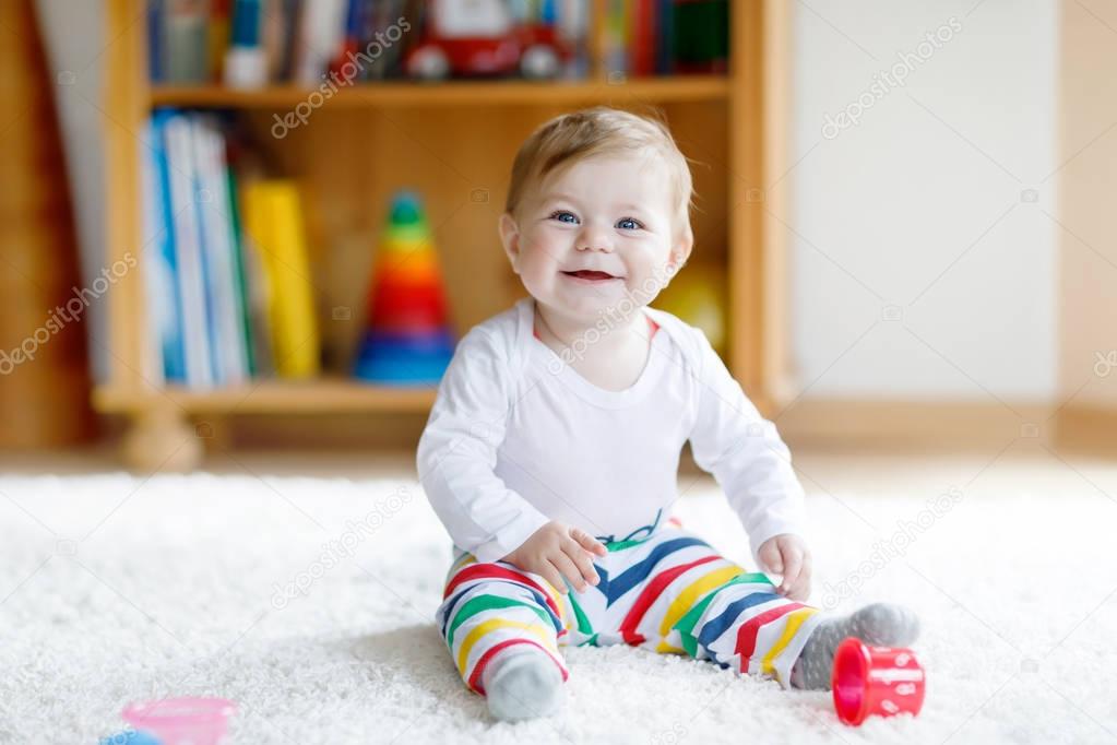 Adorable baby girl playing with educational toys in nursery