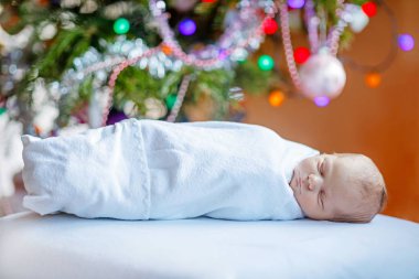 Noel ağacı yakınındaki battaniyeye sarılmış bir hafta eski yeni doğan bebek