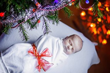 Noel ağacı yakınındaki battaniyeye sarılmış bir hafta eski yeni doğan bebek