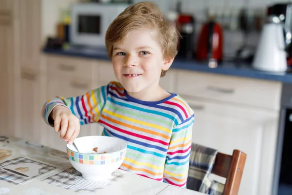 Glücklicher kleiner blonder Junge, der Müsli zum Frühstück oder Mittagessen isst. Gesunde Ernährung für Kinder. — Stockfoto