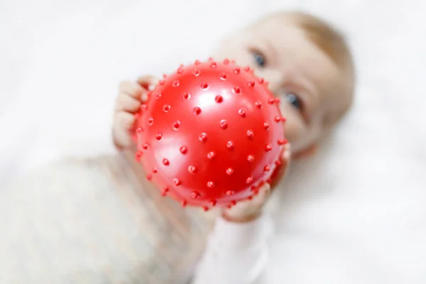 Tatlı bebek kırmızı sakız topuyla oynuyor, sürünüyor, kavrıyor — Stok fotoğraf