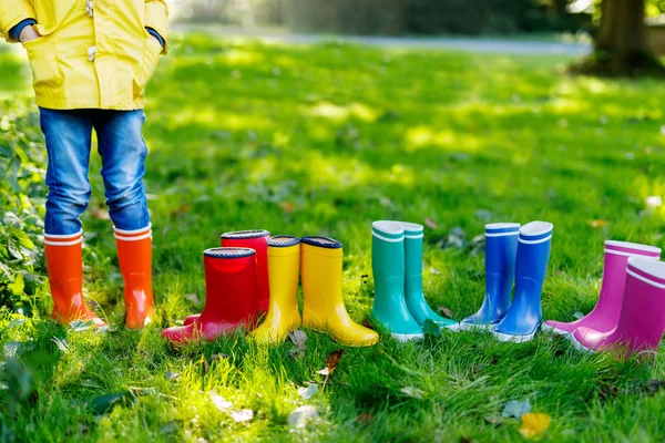 Малыш, мальчик или девочка в джинсах и желтой куртке в разноцветных сапогах дождя . — стоковое фото