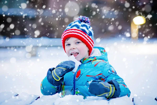 Mutlu çocuk kışın karla eğleniyor.