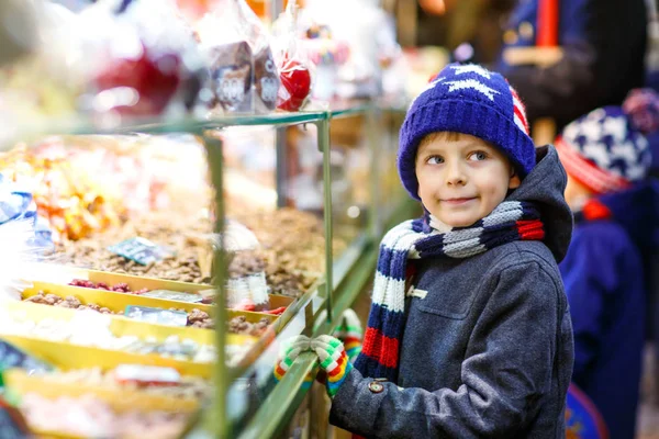 ジンジャーブレッドとお菓子と子供男の子がクリスマス マーケットの上に立つ — ストック写真