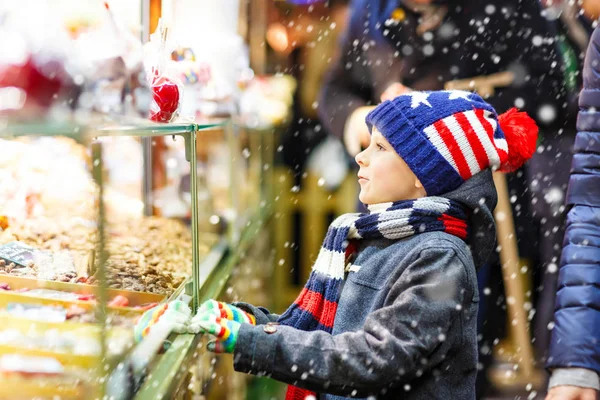 Jongen-jongetje met peperkoek en snoep staan op de kerstmarkt — Stockfoto
