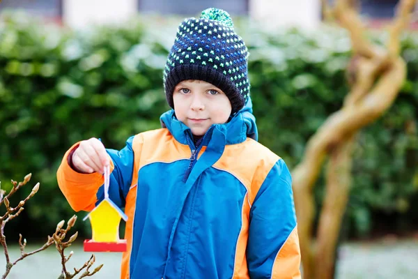 Niño colgando casa de pájaros en el árbol para alimentarse en invierno —  Fotos de Stock