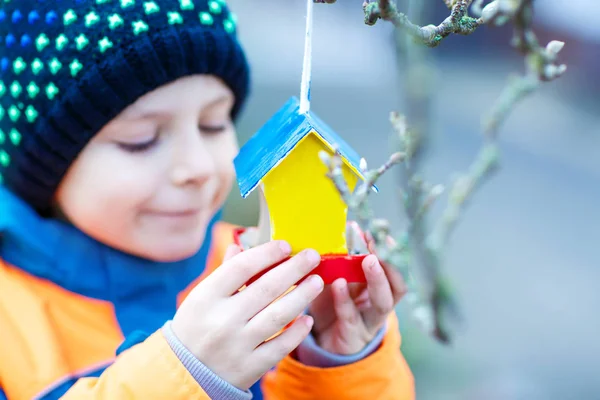 Niño colgando casa de aves en el árbol para alimentarse en invierno —  Fotos de Stock