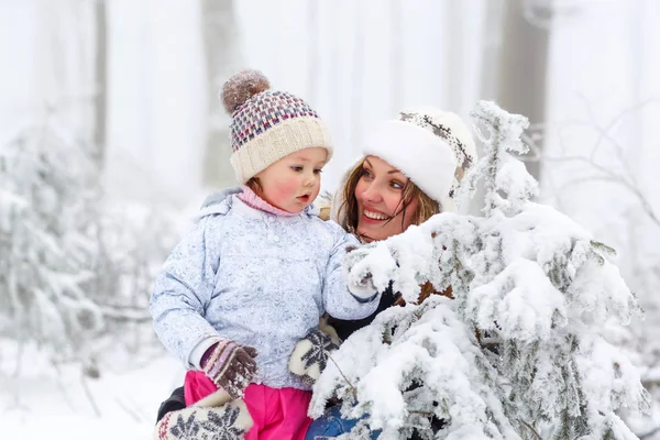 Glückliche Familie mit junger Mutter und kleiner Tochter auf einem Winterspaziergang im Freien. — Stockfoto