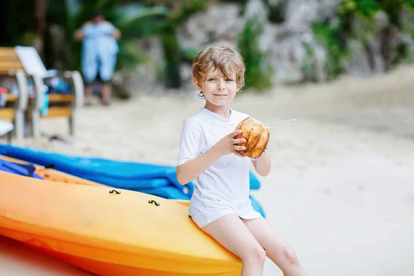 Niño bebiendo jugo de coco en la playa tropical — Foto de Stock