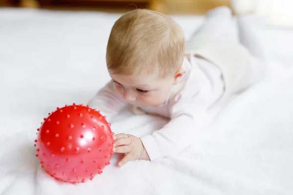 Söt baby leka med rött tuggummi boll, krypa, ta tag — Stockfoto
