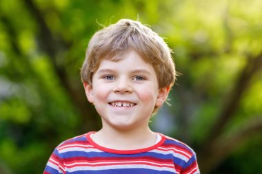 Güzel gülümseyen çocuk çocuk portresi. Yeşil ağaç arka plan karşı mutlu çocuk