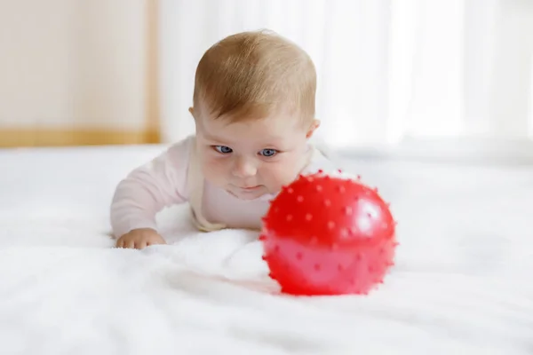 Niedliches Baby spielt mit rotem Gummiball, kriecht, greift zu — Stockfoto