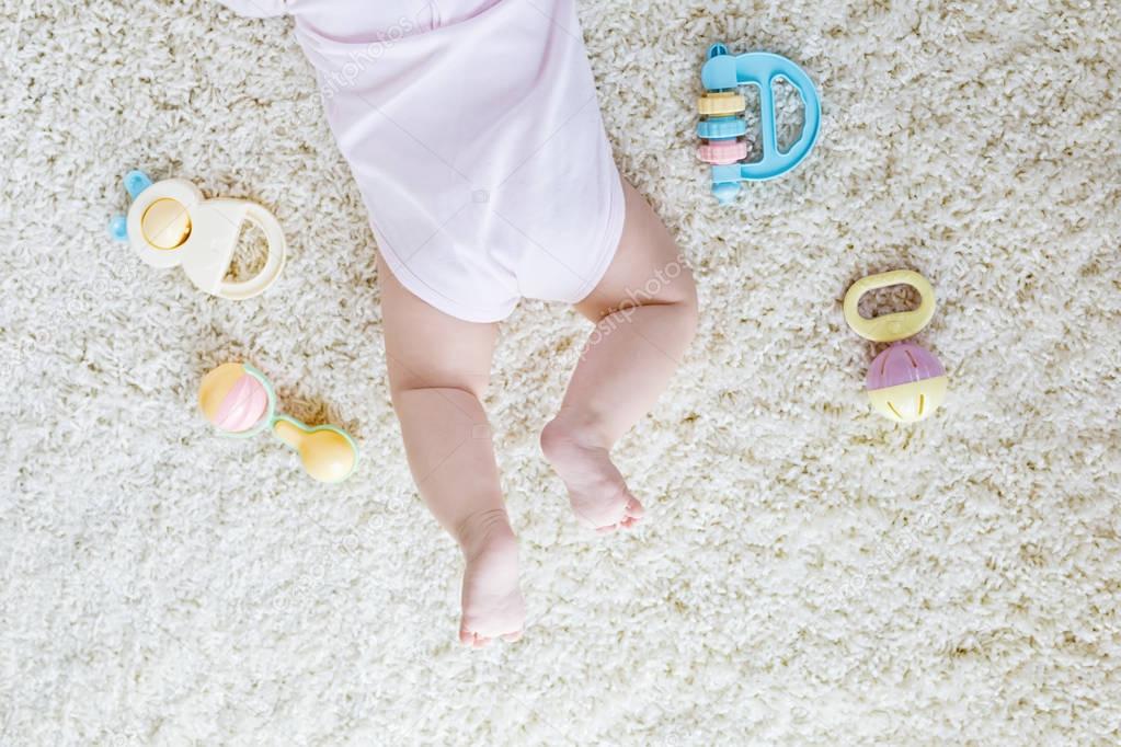 Close-up of baby body and legs with lots of colorful rattle toys.