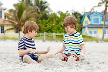 İki küçük çocuk tropik sahilde eğleniyor.