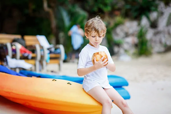 Little kid boy drinking coconut juice on tropical beach — Stock Photo, Image