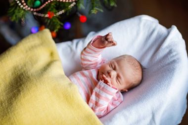 One week old newborn baby girl sleeping near Christmas tree clipart